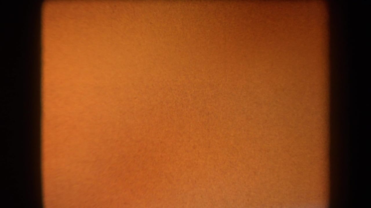 Warm orange film leader with dark vertical frame borders.
