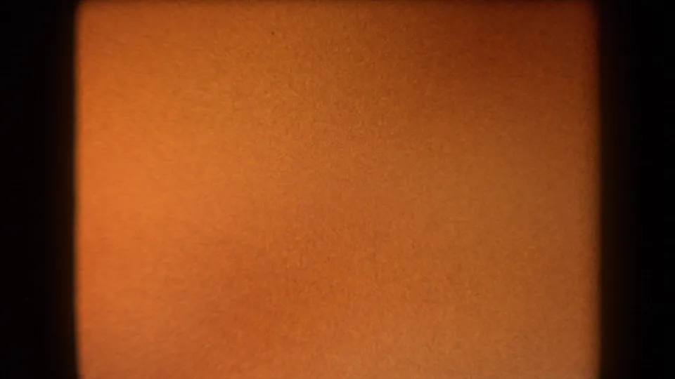 Warm orange 8mm leader fills the frame, with dark borders and fine grain preceding the Arizona canyon view.