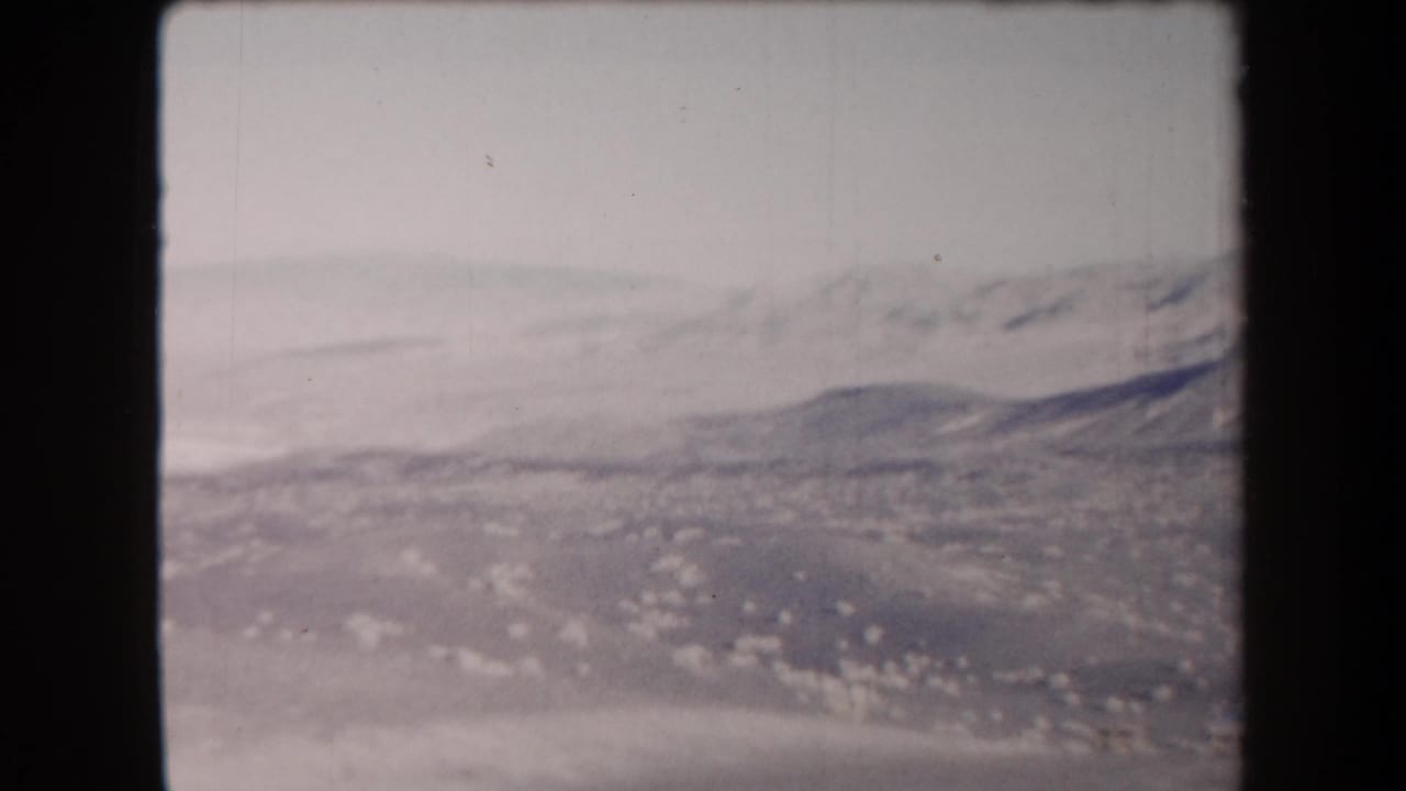 Wide arid valley beneath a gray sky with low mountains in the distance.