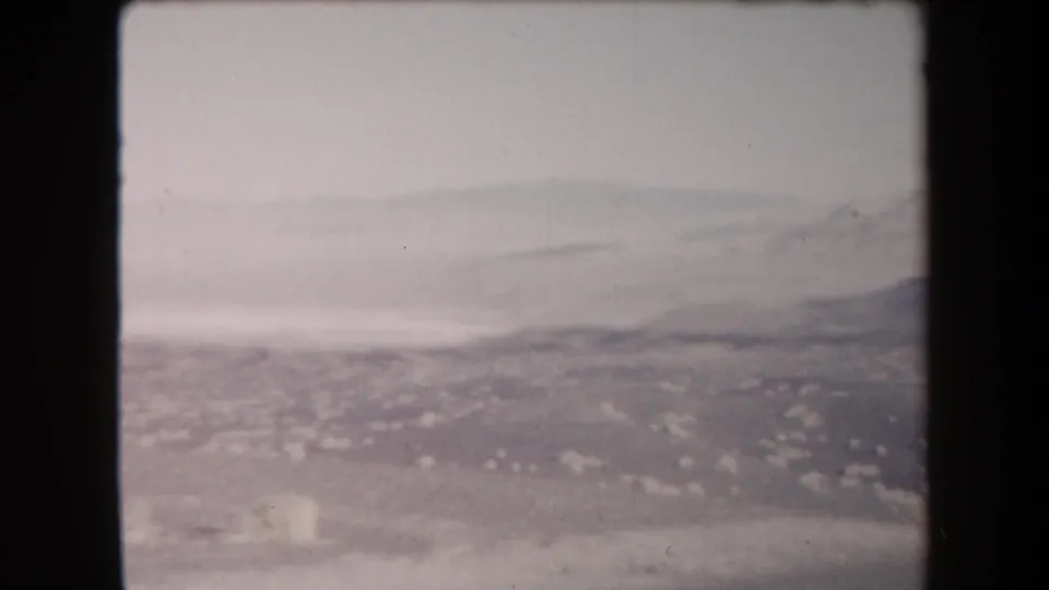 1958 Arizona 8mm view of pale desert flats and distant ridges, with heavy haze and faded color.
