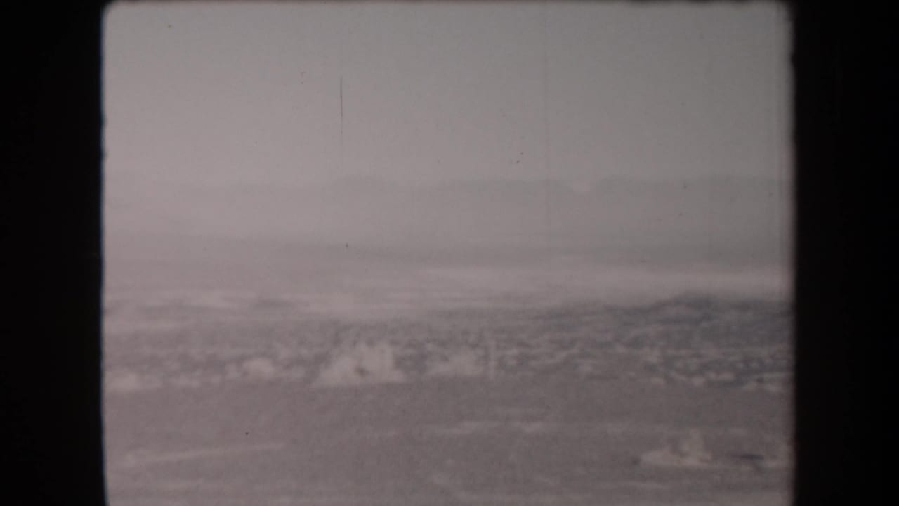 1958 Arizona 8mm frame showing a soft, smoke-obscured landscape with dark film borders and little visible human detail.