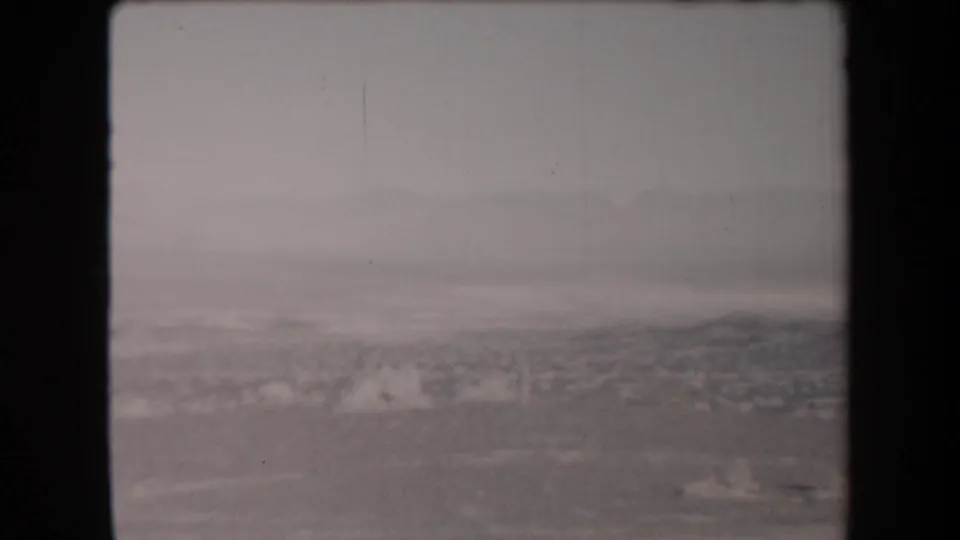 1958 Arizona 8mm frame showing a soft, smoke-obscured landscape with dark film borders and little visible human detail.