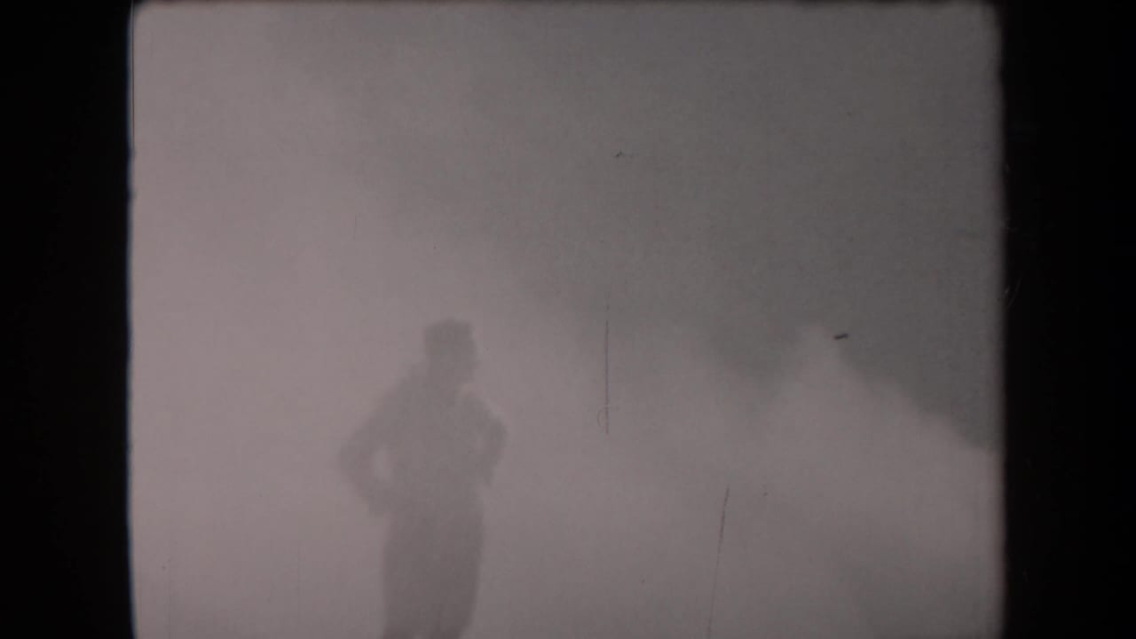 A lone figure in military-style clothing stands in dense smoke in the metadata-supported 1958 Arizona footage.
