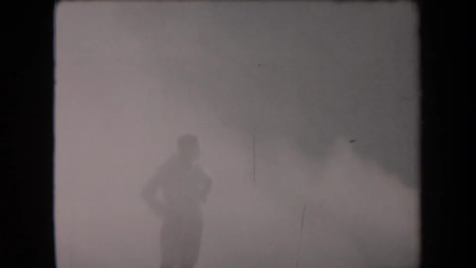 A lone figure in military-style clothing stands in dense smoke in the metadata-supported 1958 Arizona footage.