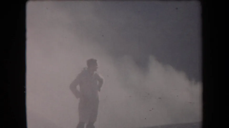 In the 1958 Arizona 8mm footage, a uniformed figure stands partly silhouetted beside a broad smoke cloud.