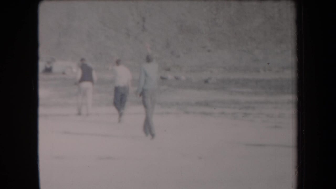 Young men walk away across a bright sandy Arizona desert landscape in 1958 home-movie footage.