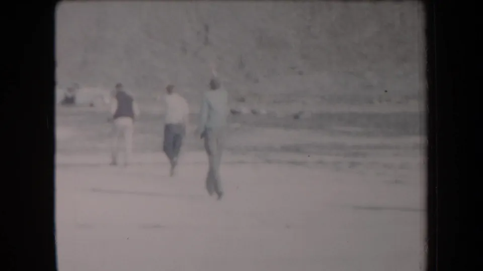 Young men walk away across a bright sandy Arizona desert landscape in 1958 home-movie footage.