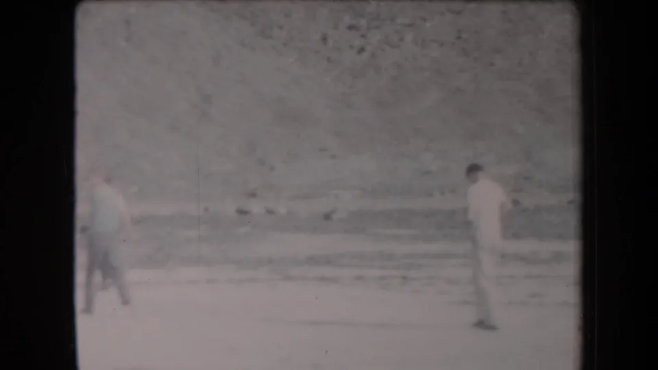 Distant young men walk through a sparse sandy desert setting in Arizona, filmed on 8mm in 1958.