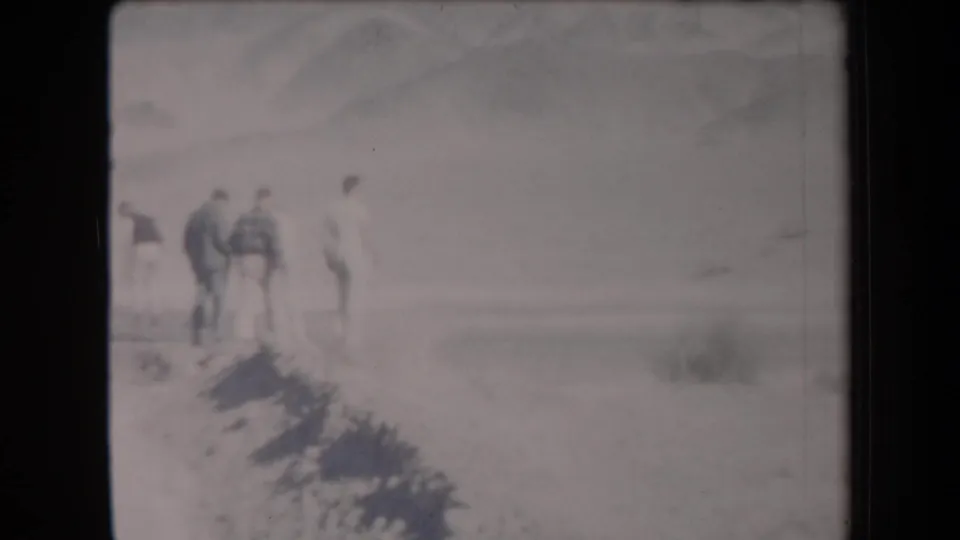Young men gather or walk near a sandy edge in the Arizona desert, seen in soft 1958 8mm footage.