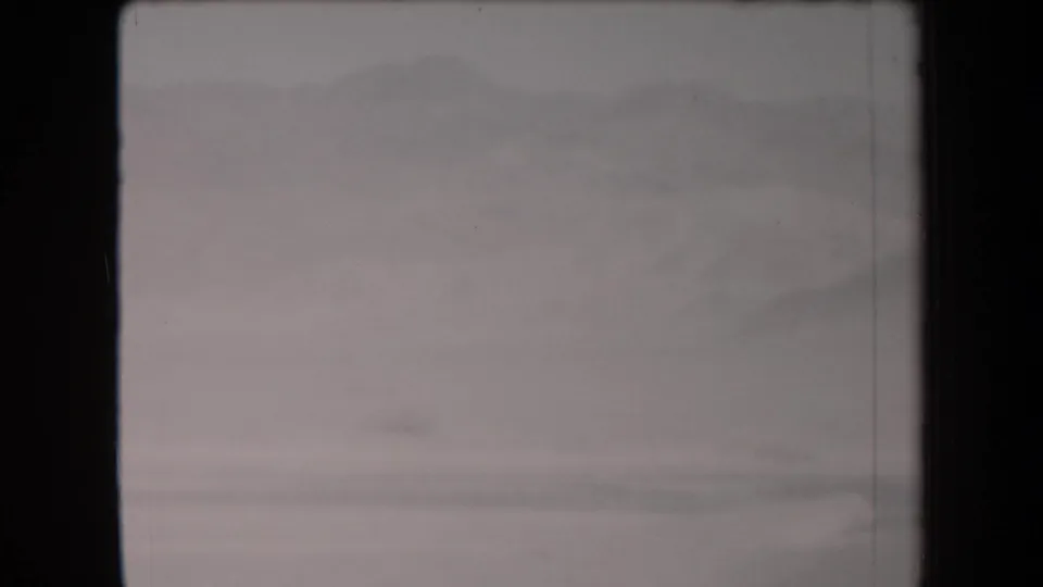 Washed-out 1958 Arizona desert frame showing pale ground, a distant mountain range, and soft 8mm exposure.