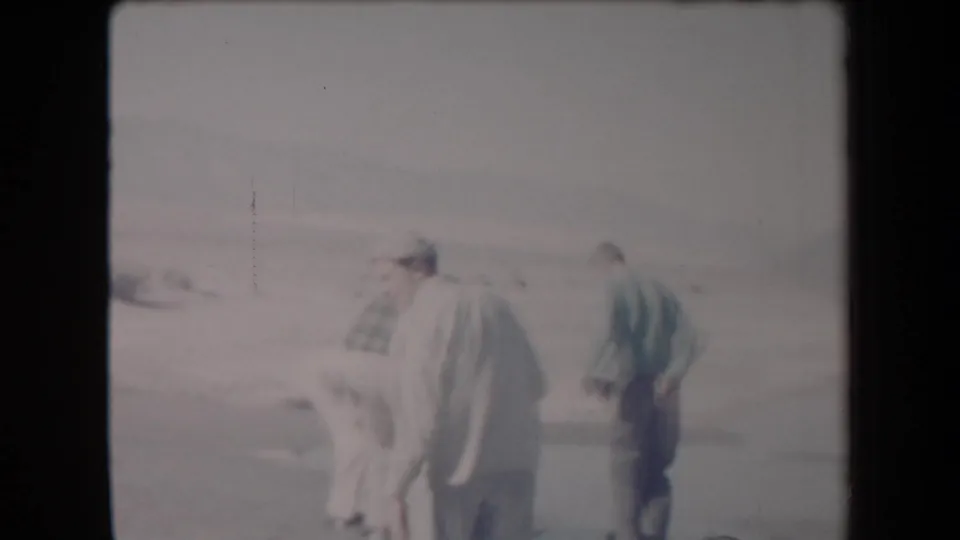 Adult men, one in a light suit and hat, stand together in an Arizona desert setting in 1958 home-movie footage.