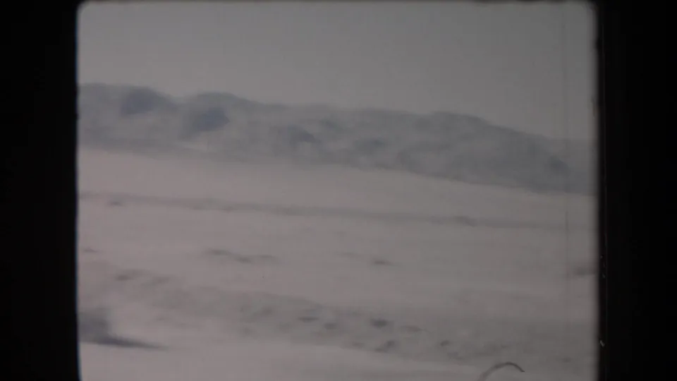 1958 Arizona 8mm frame showing a pale desert landscape and soft mountain ridge in the distance.