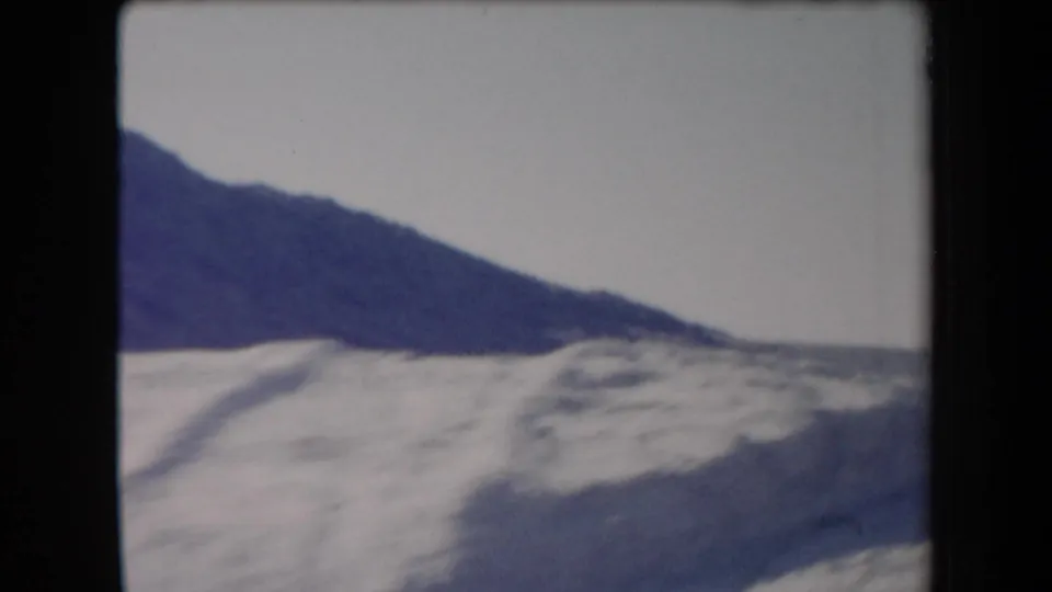 1958 Arizona 8mm view of a dark desert ridge and pale sandy ground, softly framed by the film edge.