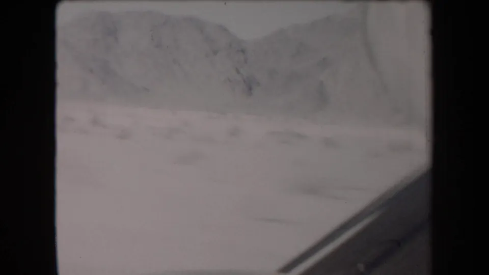 1958 Arizona road-trip frame with desert hills, pale terrain, and a partial vehicle edge visible at the lower right.