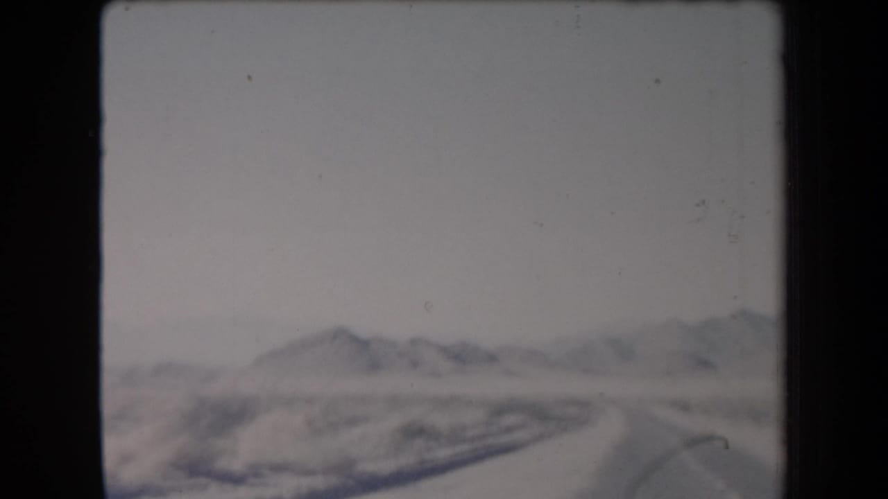 Soft desert landscape with distant mountains seen through grainy film.