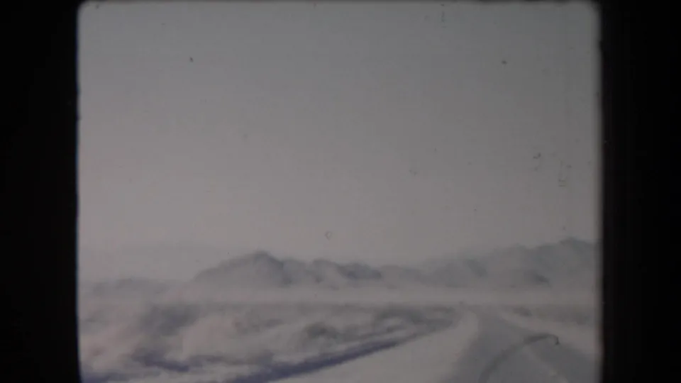 Blurry 1958 Arizona home-movie view of dry desert terrain and distant mountains through soft 8mm focus.