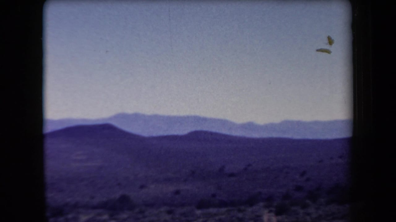 1958 Arizona home-movie view of rolling desert hills, distant mountain layers, pale sky, and visible film-frame edges.