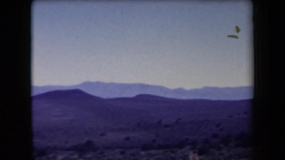 1958 Arizona home-movie view of rolling desert hills, distant mountain layers, pale sky, and visible film-frame edges.