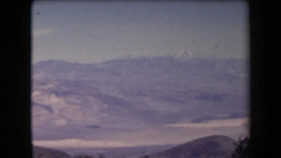 1958 Arizona 8mm frame with faded color, showing a broad valley floor, distant mountains, and low foreground hills.