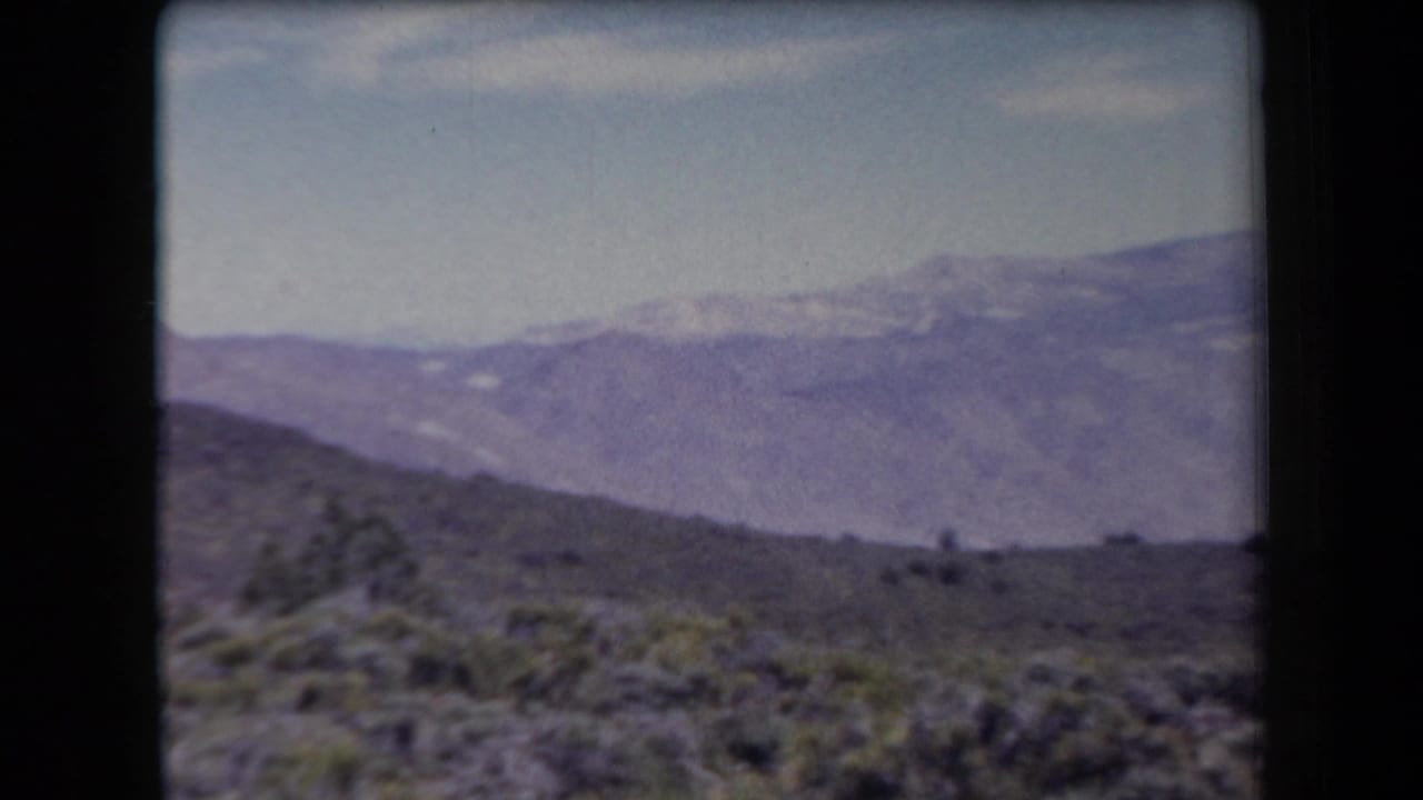 1958 Arizona home-movie view of scrubby desert hills and hazy mountain ranges in the distance.