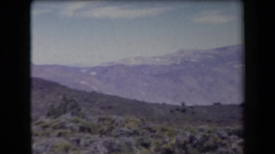 1958 Arizona home-movie view of scrubby desert hills and hazy mountain ranges in the distance.