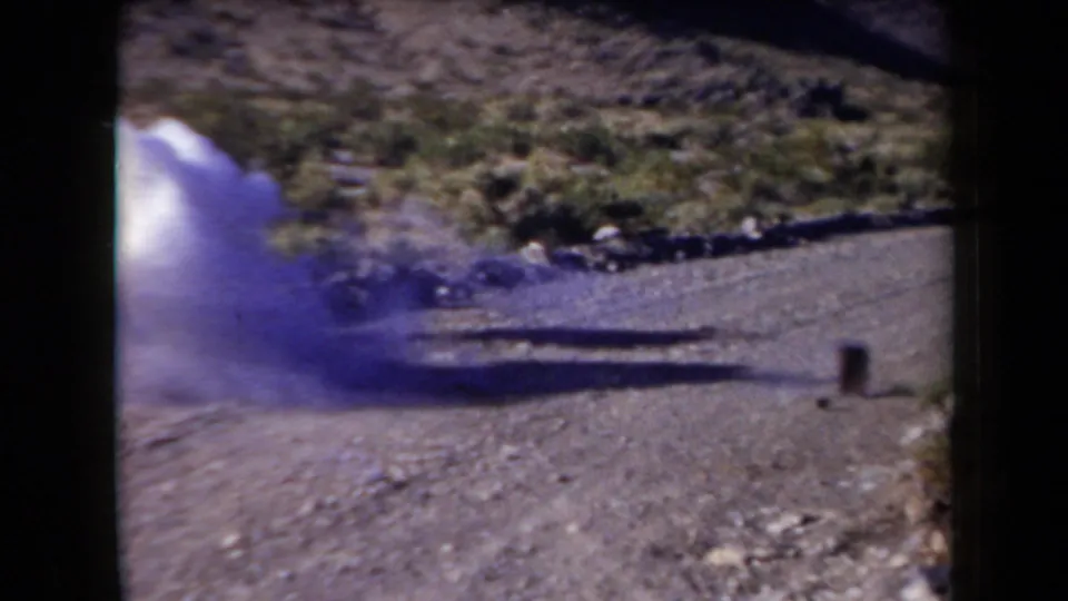 1958 Arizona frame with a smoke burst near the roadside can target during apparent shooting practice.
