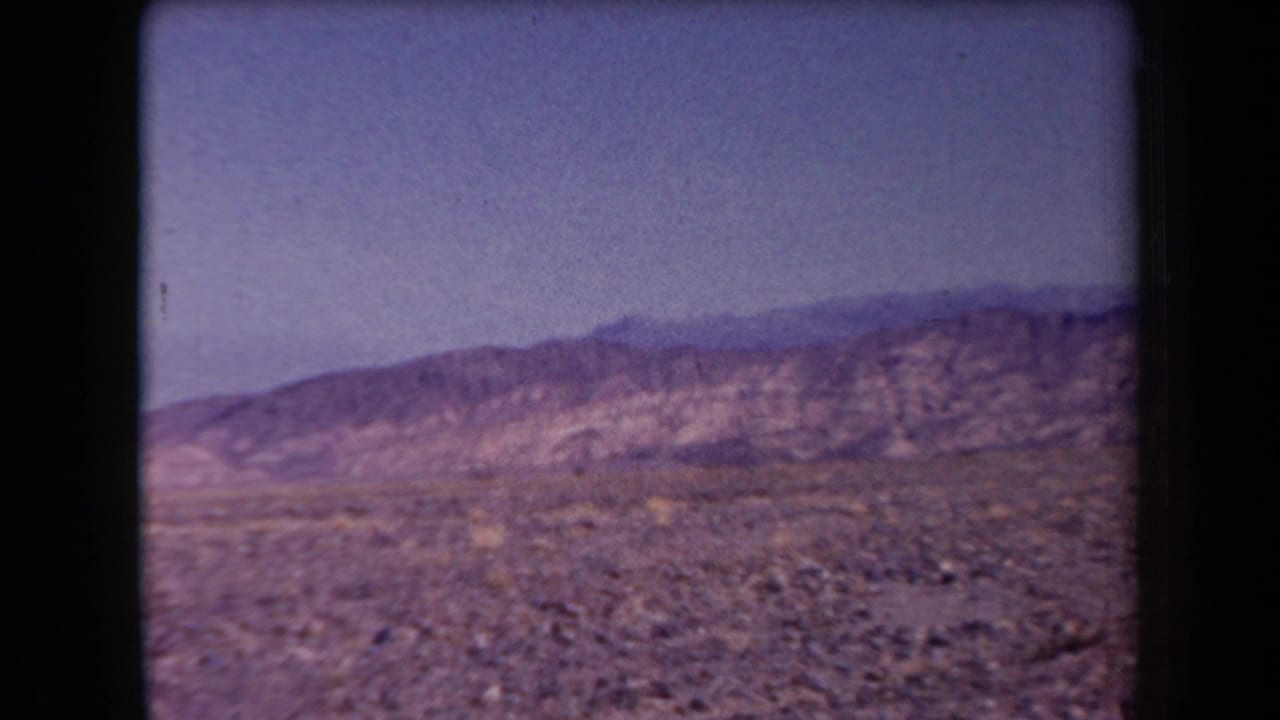 Open desert floor with low mountain ridges beneath a hazy sky.