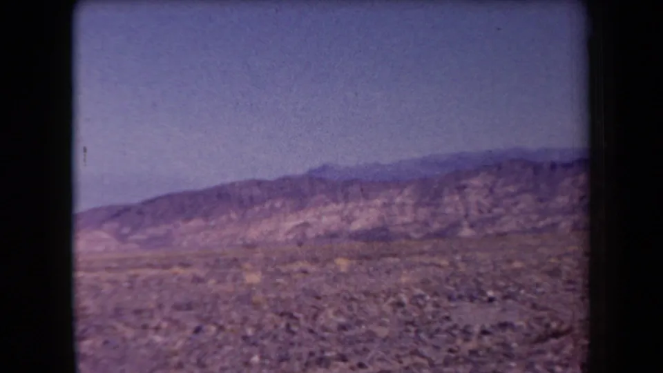 1958 Arizona home-movie view of open rocky desert and distant mountains under a blue-tinted sky.