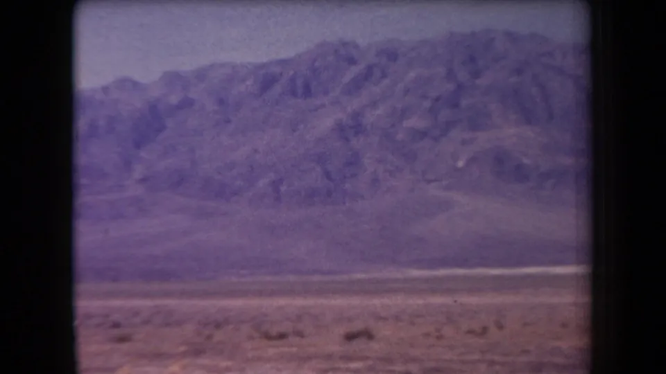 1958 Arizona 8mm view of a mountain ridge above an arid foreground, softened by motion blur and aged film color.