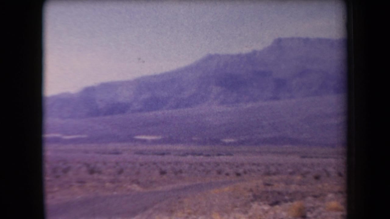 Open desert with a faint road or track leading toward mountains.