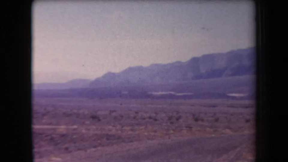 1958 Arizona home-movie view of a wide desert valley, low brush, and distant mountains softened by exposure and motion.