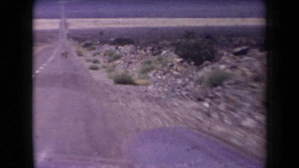 Arizona road-trip footage from 1958 appears to show a paved highway receding through rocky desert terrain.