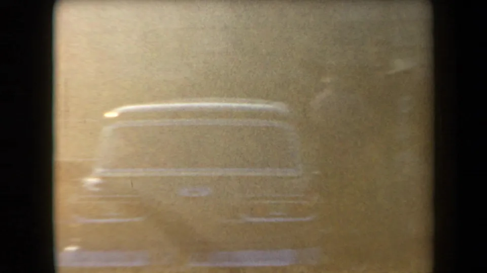 Faded 1958 Arizona home-movie frame with the rear outline of a mid-century car in overexposed light.