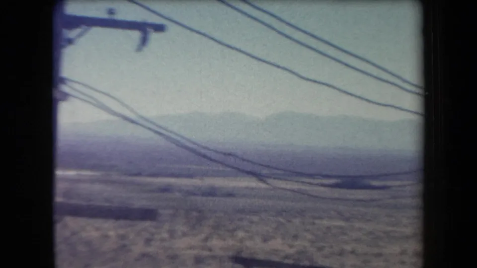 1958 Arizona home-movie view of utility lines in the foreground against a hazy desert landscape and distant mountains.