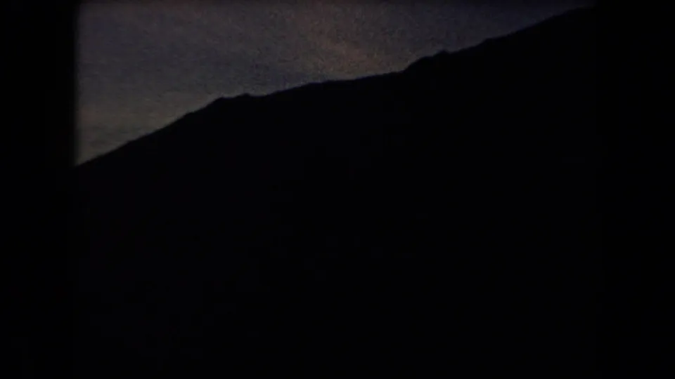 Arizona 1958 home-movie frame showing a silhouetted mountain ridge and dark valley at dusk.