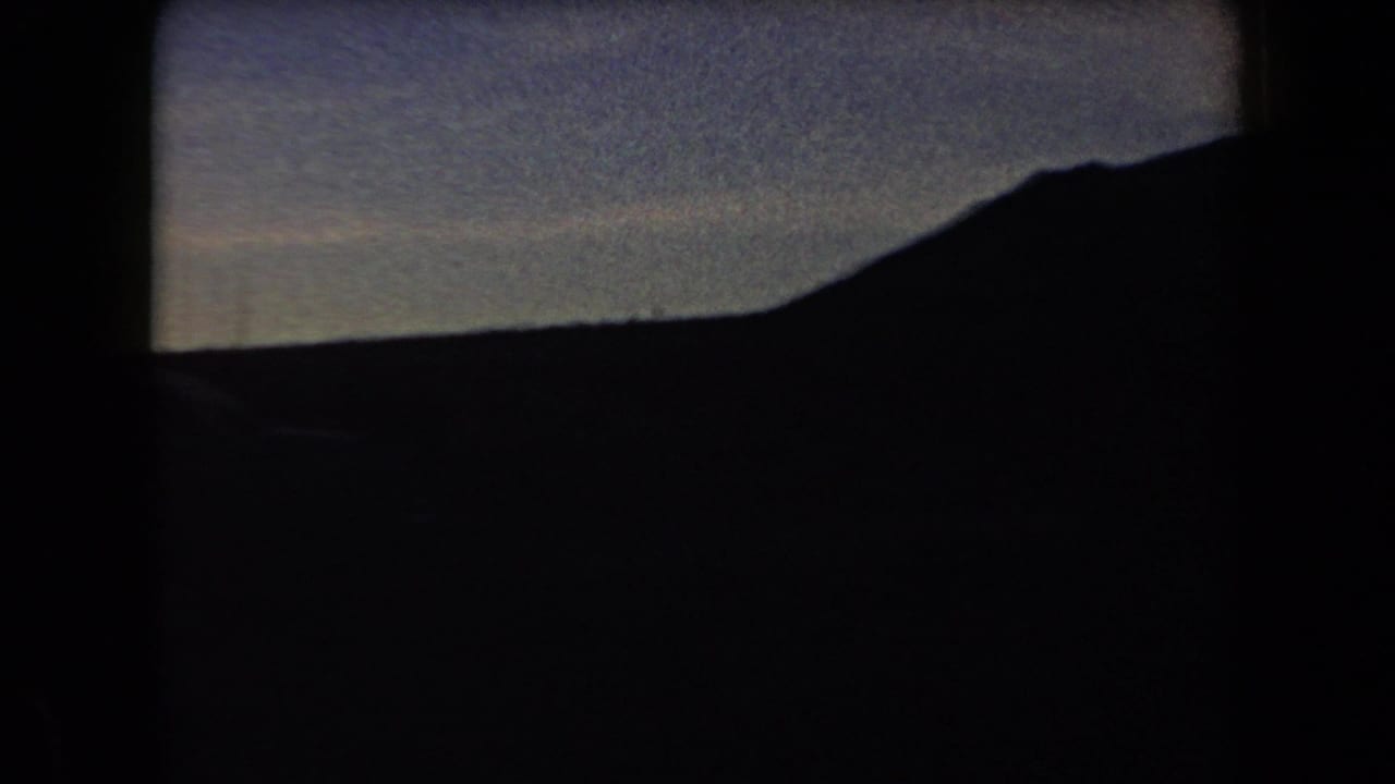 Silhouetted mountains and open valley beneath a twilight sky.