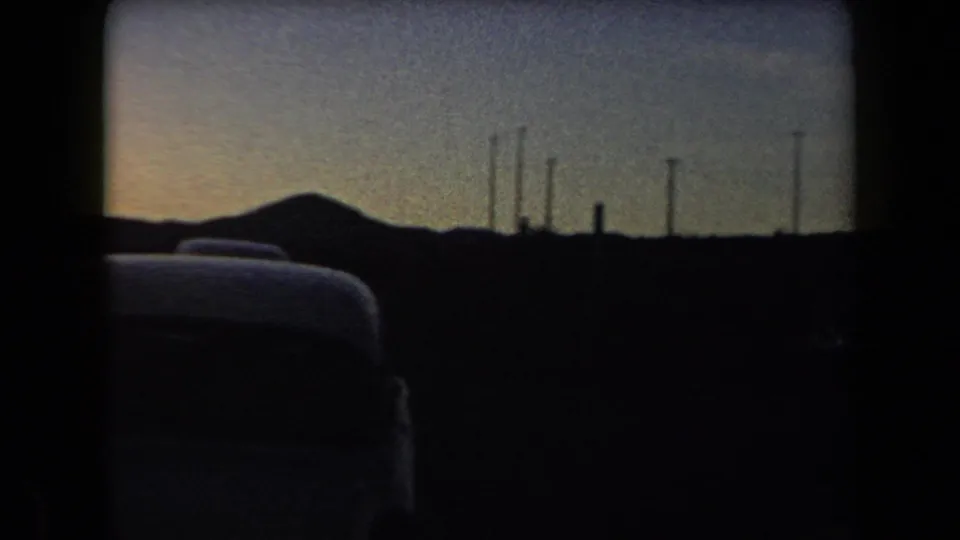 Arizona 1958 dusk frame with classic cars, roadside utility poles, and low hills silhouetted against the sky.