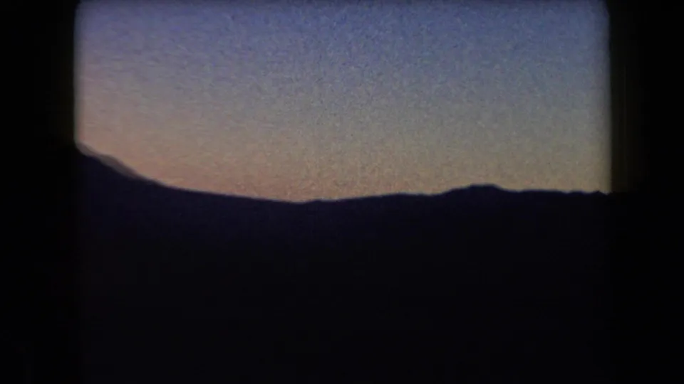 1958 Arizona 8mm frame with a silhouetted mountain outline and blue-to-orange dusk sky, framed by visible film borders.