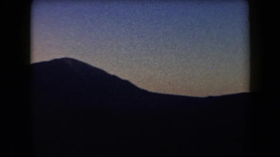 1958 Arizona home-movie frame showing a dark mountain silhouette against a fading twilight sky.
