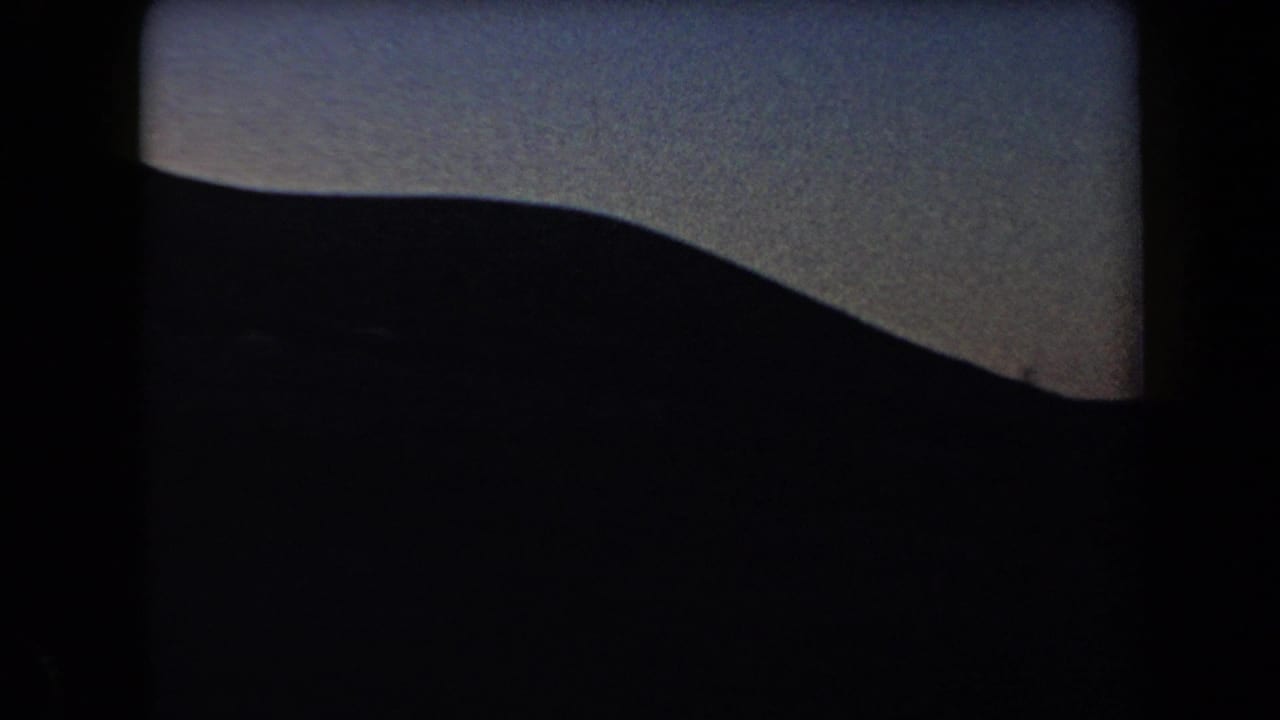 Large dark mountain slope filling the lower frame beneath a dim sky.