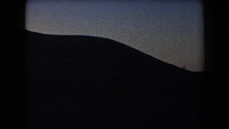 Arizona home-movie frame from 1958 with a broad mountain slope nearly black against the evening sky.