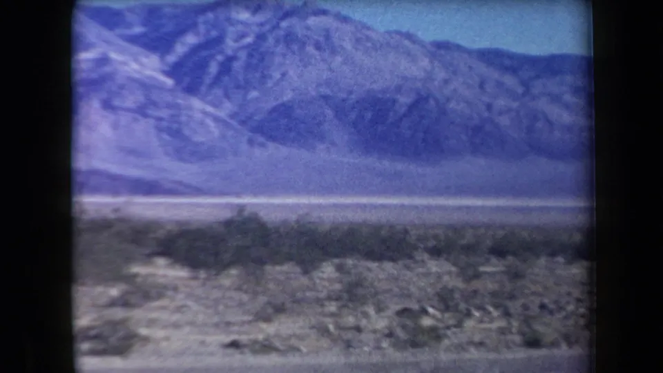 1958 Arizona home-movie view of desert scrubland and rugged mountains filmed from a moving vehicle.