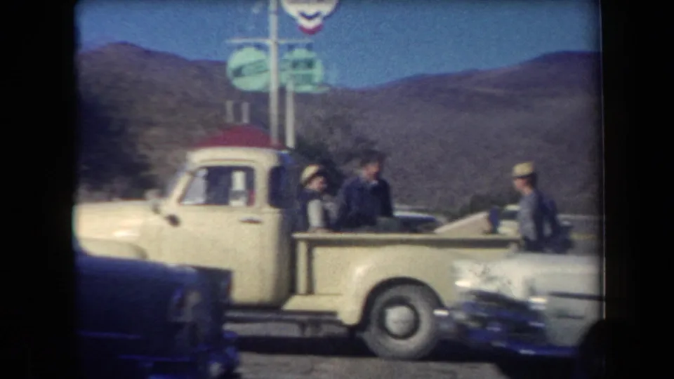 A 1958 Arizona roadside stop shows a pickup, parked cars, a green sign, and travelers standing near the vehicles.