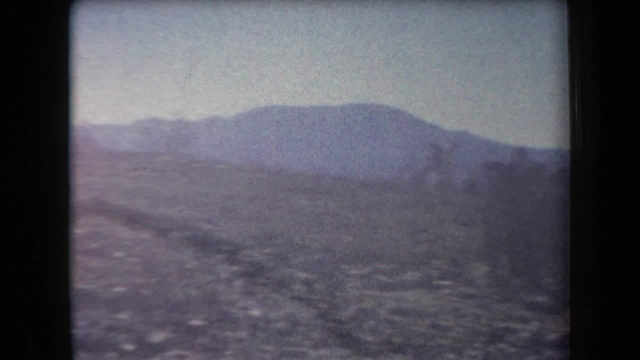 1958 Arizona home-movie view of a distant mountain ridge across rocky open desert terrain.