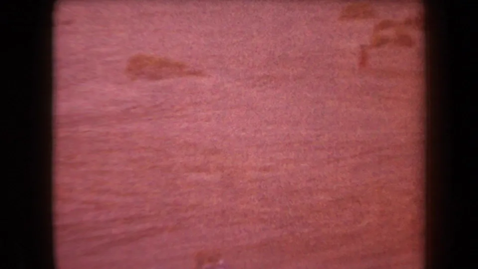 Red-shifted 8mm frame of sandy Arizona desert terrain with faint dune contours and strong film grain.