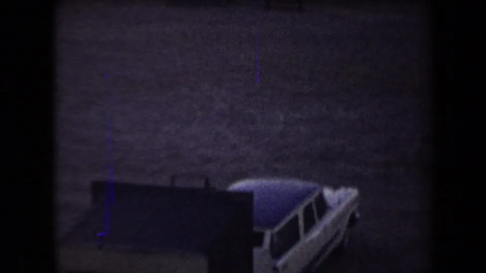 1958 Arizona home-movie frame showing a light-colored classic car near a dark object on dry ground.