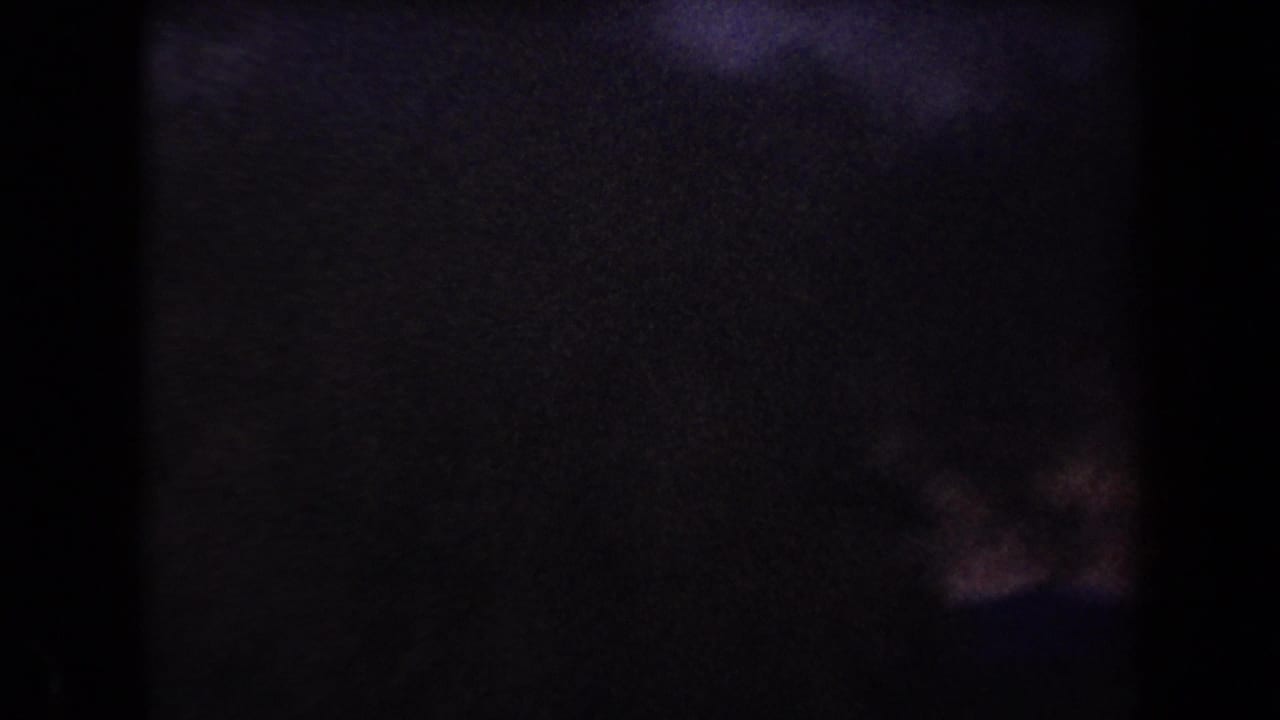 Underexposed 8mm frame from the Arizona clip, with faint dusk color and barely visible horizon detail after the ignition.