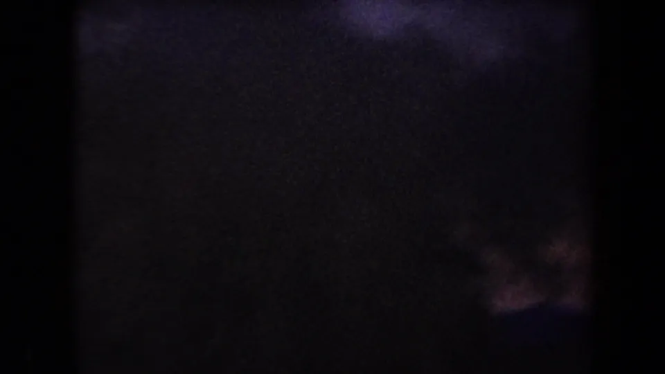 Underexposed 8mm frame from the Arizona clip, with faint dusk color and barely visible horizon detail after the ignition.