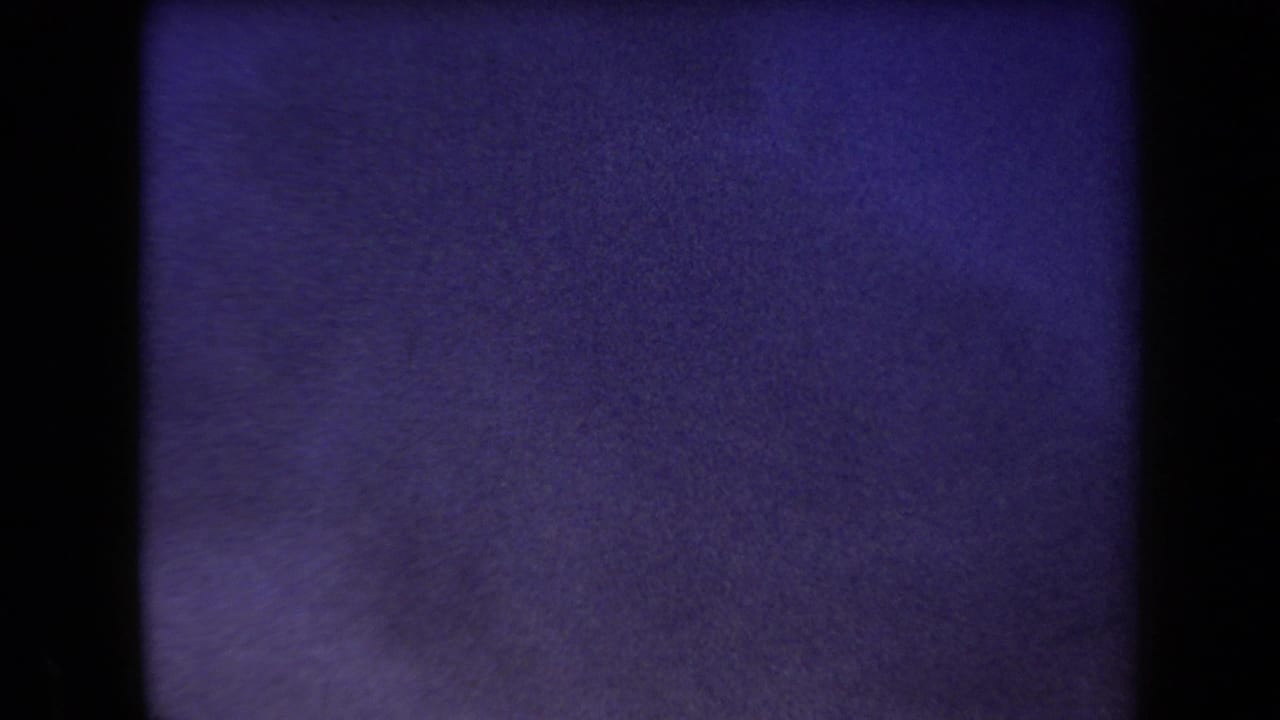 1958 Arizona 8mm frame dominated by purple film grain, dark rounded borders, and an indistinct pale field.