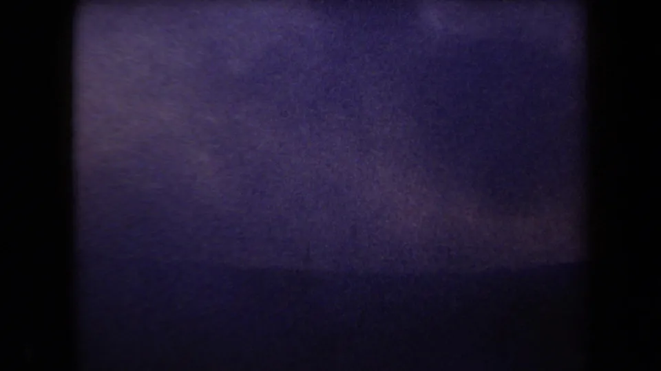 1958 Arizona 8mm frame with purple color shift, heavy grain, dark borders, and faint horizontal banding.
